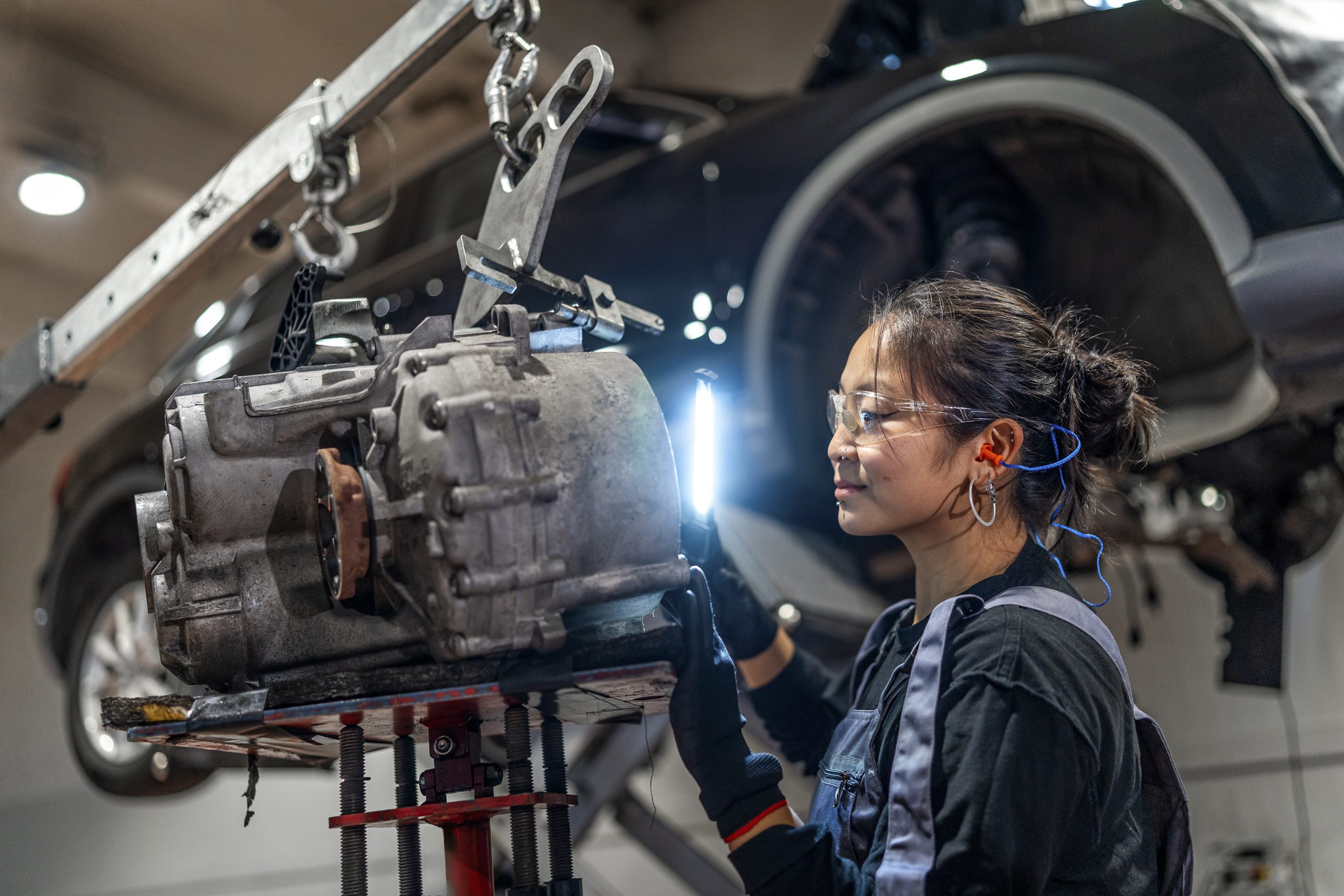 A female apprentice working with a car engine.